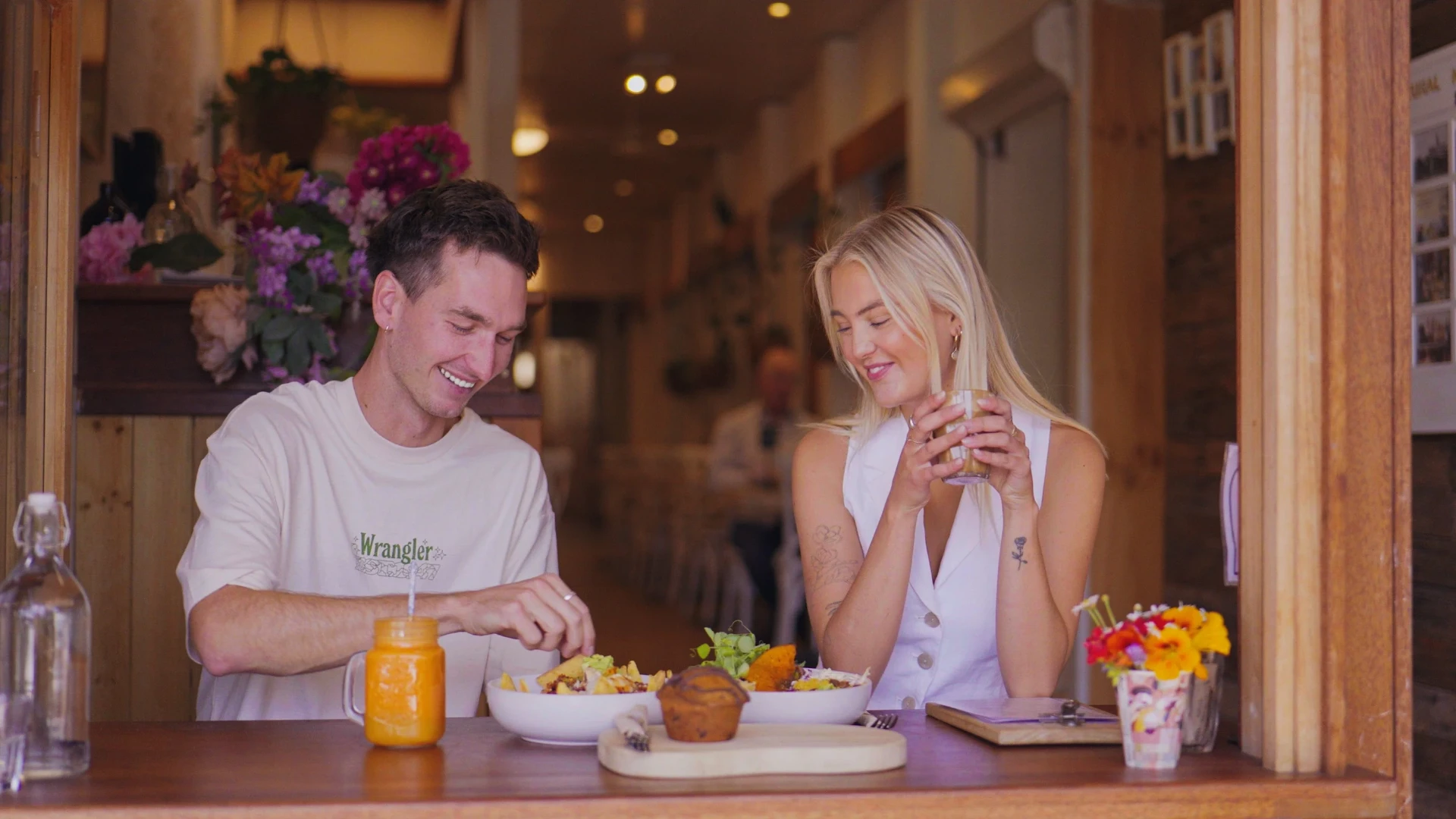 Inside Perfect Break Cafe: two guests enjoying breakfast bowls and juice at the timber window counter